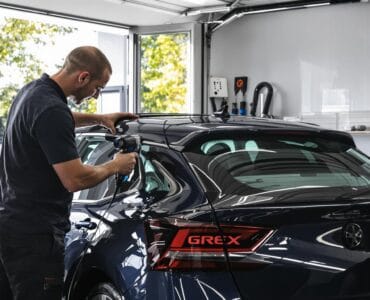 Installer using heat gun to shrink window tint in a professional garage